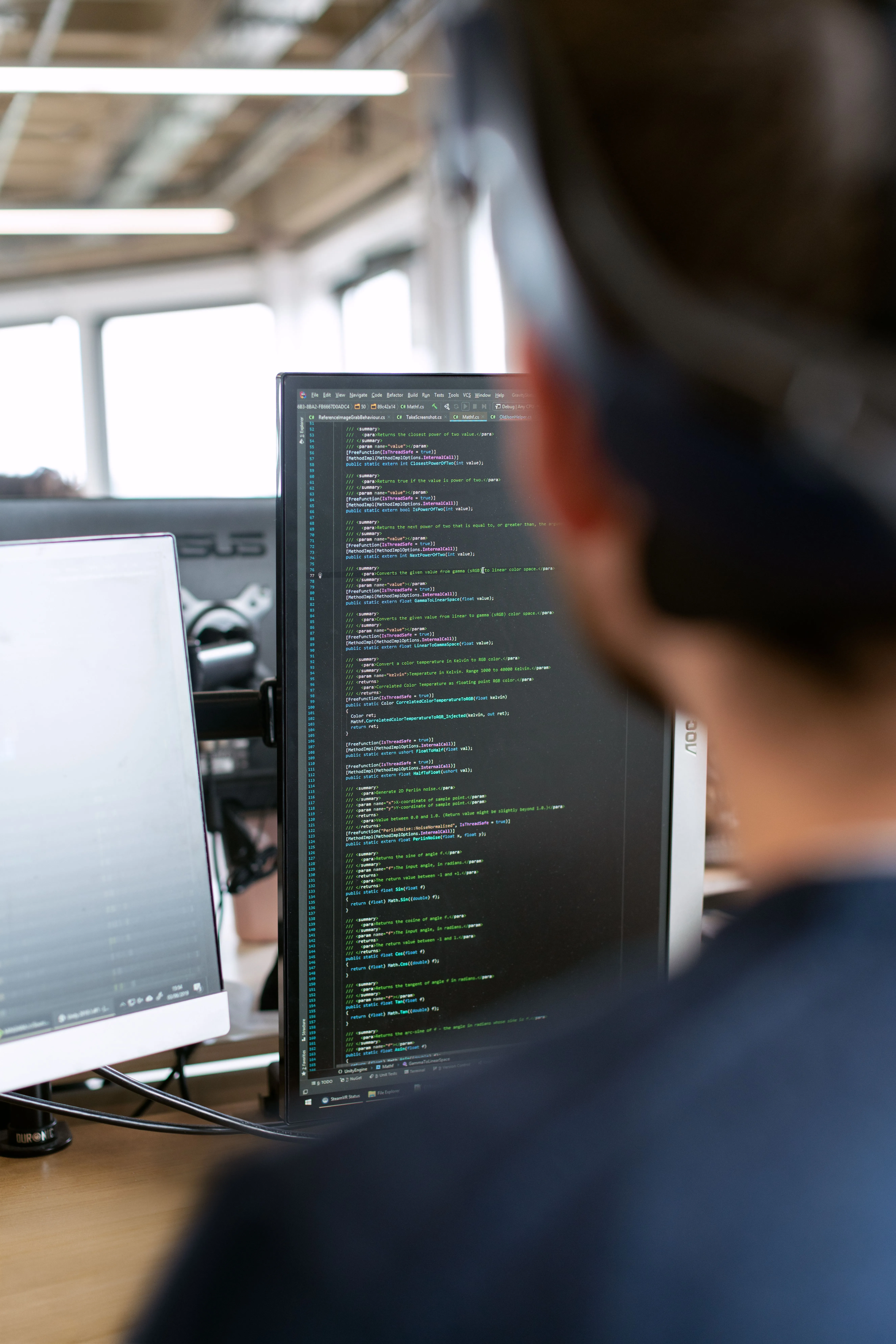 Entwickler arbeitet an einem Monitor mit Quellcode in einer Entwicklungsumgebung