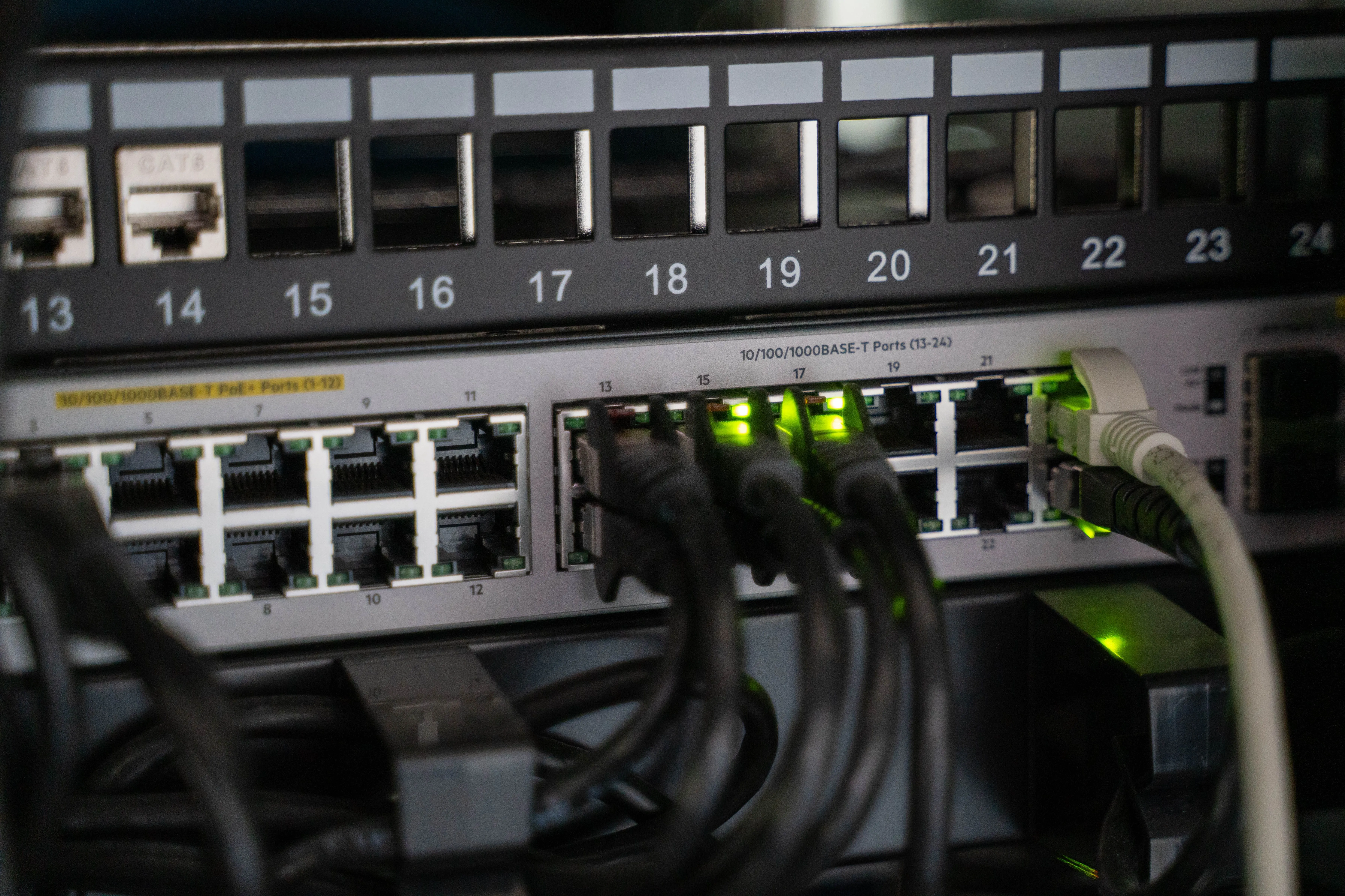 Netzwerk-Patchpanel und Switch mit eingesteckten Kabeln und aktiven Status-LEDs
